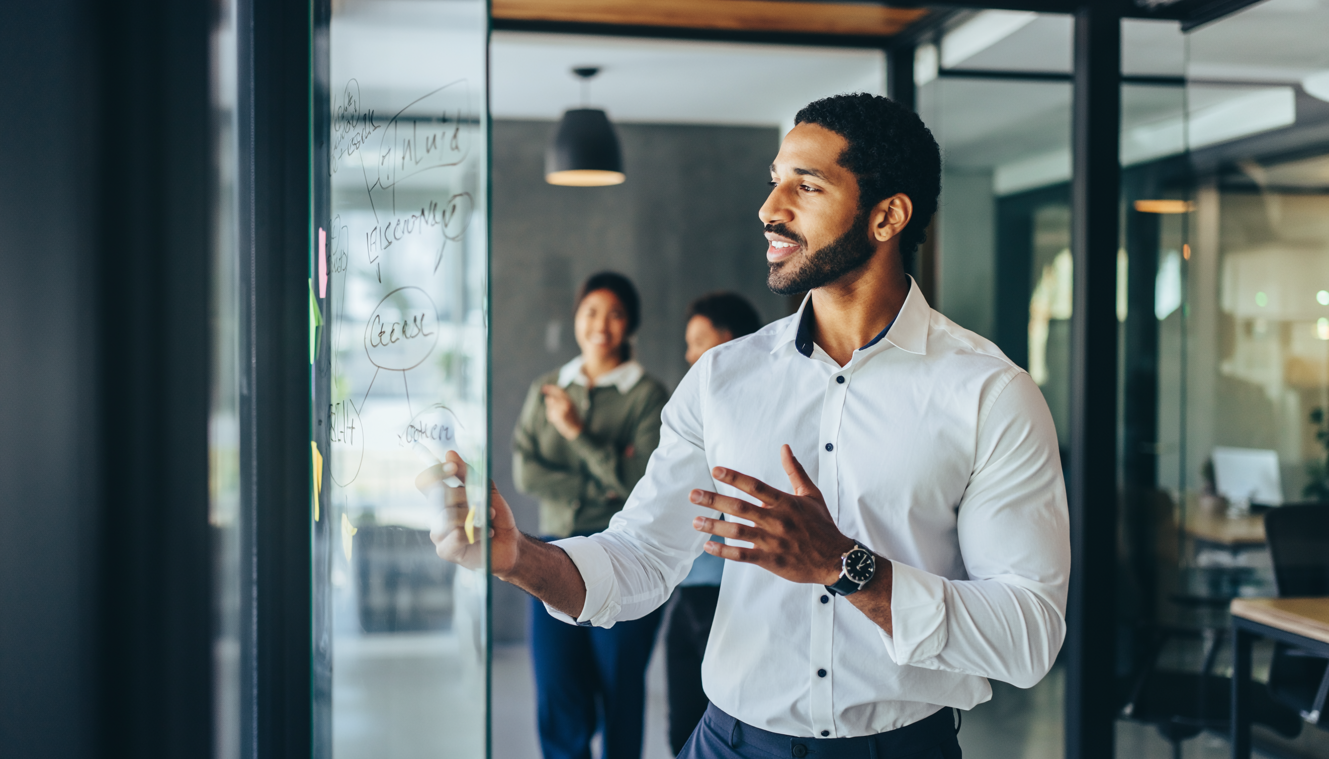 Man Presenting Ideas on Glass Board in Modern Office